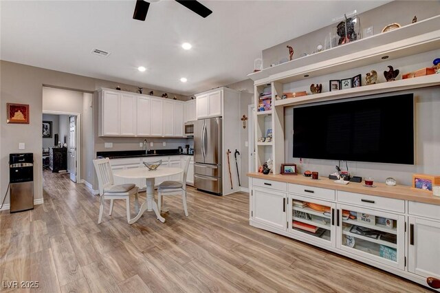 kitchen with white cabinets, light wood-type flooring, appliances with stainless steel finishes, and butcher block counters