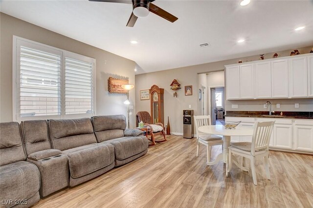 kitchen featuring sink, light wood-type flooring, ceiling fan, and white cabinetry