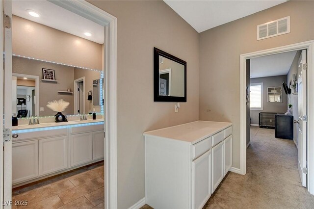 hallway with light carpet and sink