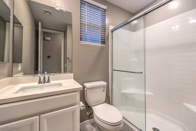 bathroom with toilet, vanity, and a shower with shower door