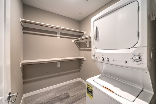 washroom with stacked washing maching and dryer and hardwood / wood-style floors