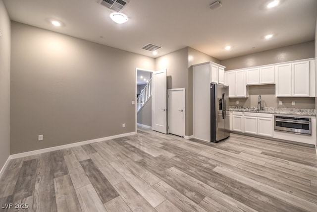 kitchen featuring stainless steel appliances, light hardwood / wood-style floors, white cabinets, and sink