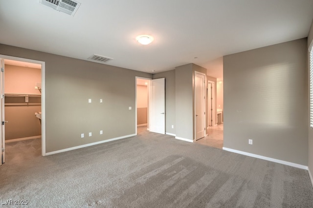 unfurnished bedroom with light colored carpet, a spacious closet, and a closet