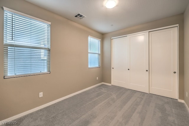 unfurnished bedroom featuring a closet and light carpet