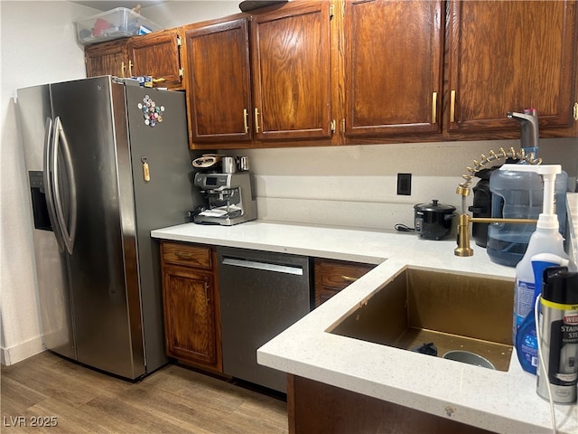 kitchen with sink, stainless steel fridge, light hardwood / wood-style flooring, and dishwashing machine