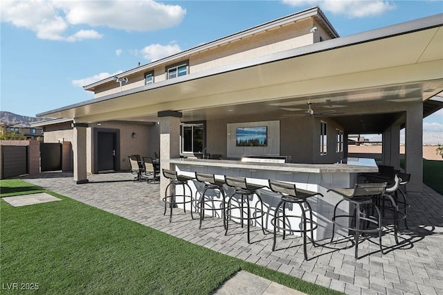 back of house with ceiling fan, a patio, and a bar