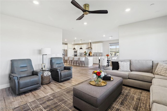 living room featuring sink, hardwood / wood-style flooring, and ceiling fan