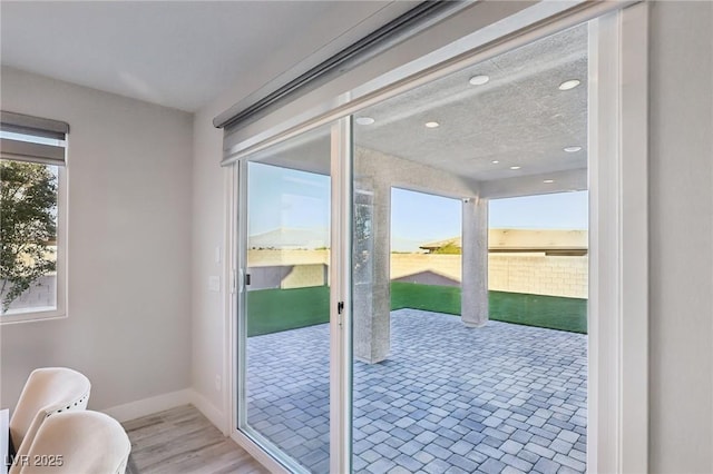 entryway with light wood-type flooring, a healthy amount of sunlight, and a textured ceiling