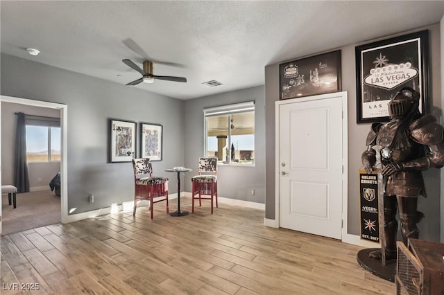 living area with light hardwood / wood-style floors, a textured ceiling, and ceiling fan