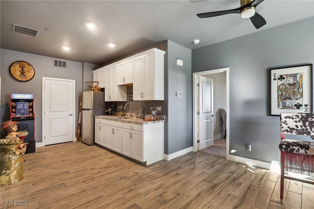 kitchen with light hardwood / wood-style floors, white cabinetry, and stainless steel fridge