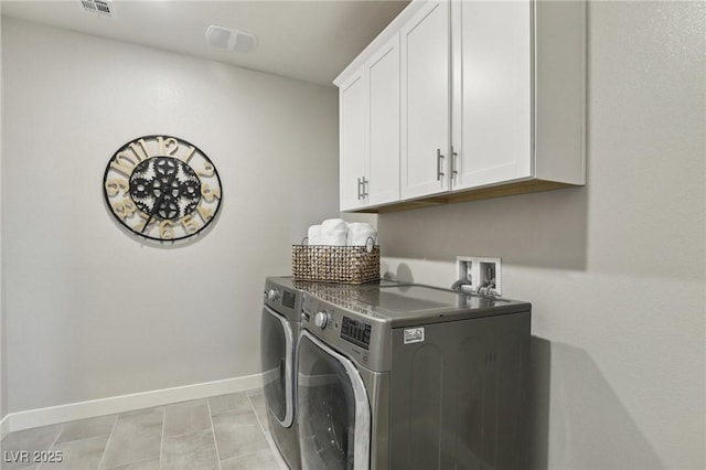 laundry room featuring cabinets, light tile patterned floors, and washing machine and clothes dryer