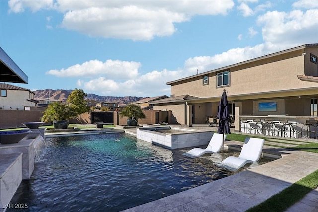 view of swimming pool with a bar, a jacuzzi, pool water feature, a mountain view, and a patio area