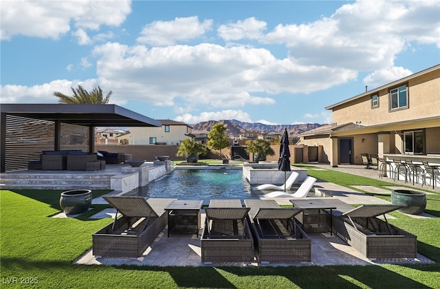 view of pool featuring exterior bar, a patio, a mountain view, a lawn, and pool water feature