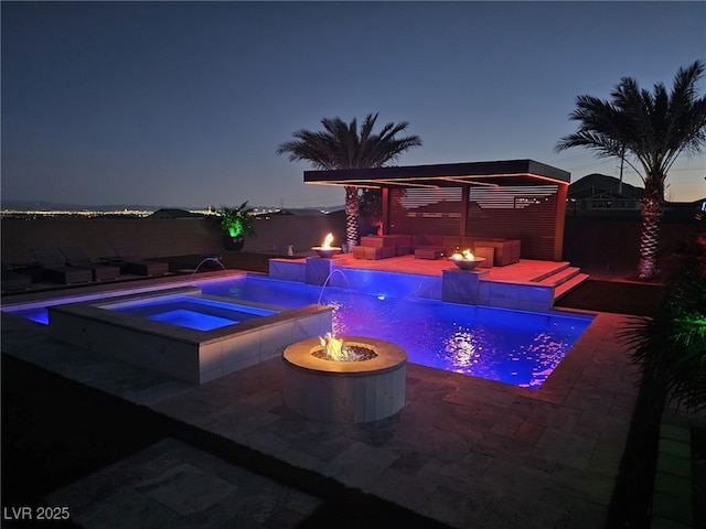 pool at dusk featuring an in ground hot tub, an outdoor fire pit, pool water feature, and a patio area