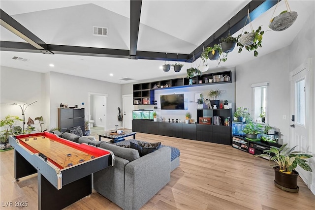 living room featuring light hardwood / wood-style floors and vaulted ceiling with beams