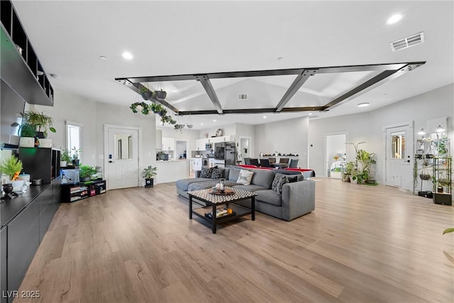 living room with light hardwood / wood-style floors and vaulted ceiling with beams