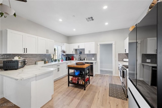 kitchen with stainless steel appliances, sink, white cabinets, light stone counters, and light wood-type flooring