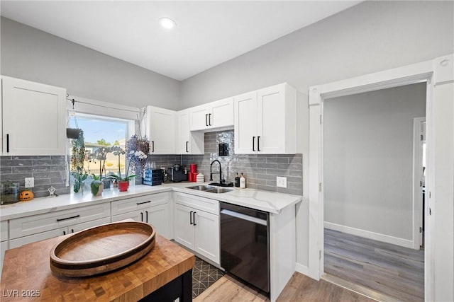 kitchen with dishwasher, light hardwood / wood-style floors, decorative backsplash, sink, and white cabinetry