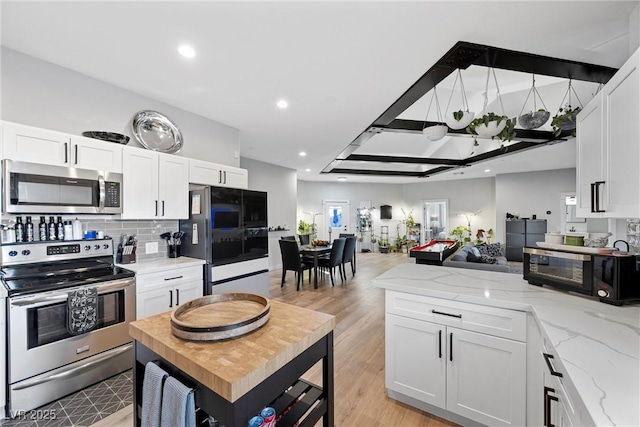 kitchen featuring appliances with stainless steel finishes, light hardwood / wood-style floors, white cabinets, and light stone counters