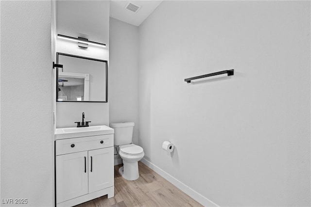 bathroom featuring toilet, vanity, and hardwood / wood-style floors