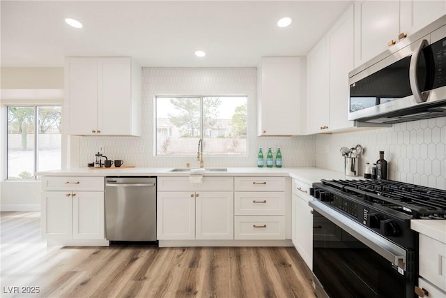 kitchen with white cabinets, light hardwood / wood-style floors, stainless steel appliances, a healthy amount of sunlight, and sink