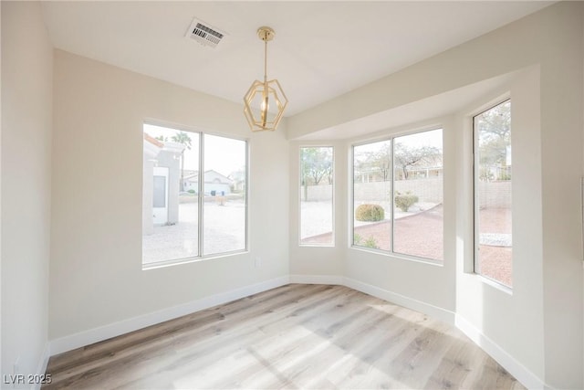 unfurnished dining area with an inviting chandelier and light hardwood / wood-style floors