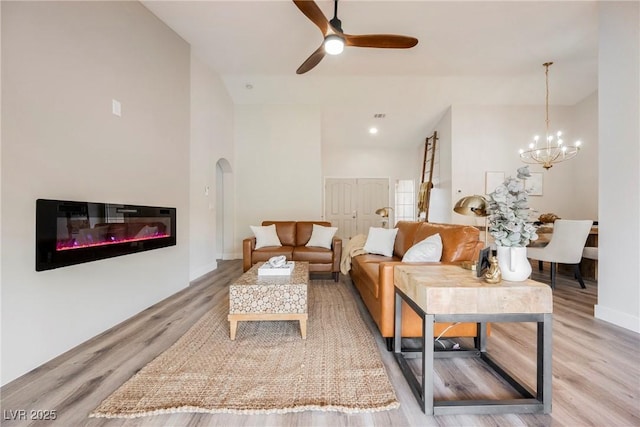 living room with ceiling fan with notable chandelier and light hardwood / wood-style floors