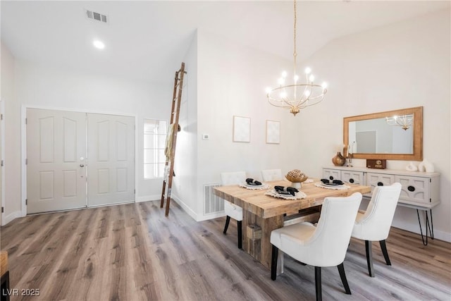 dining room featuring light hardwood / wood-style floors, a chandelier, and vaulted ceiling