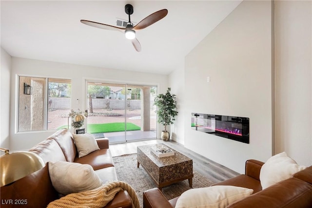 living room with ceiling fan, vaulted ceiling, and wood-type flooring