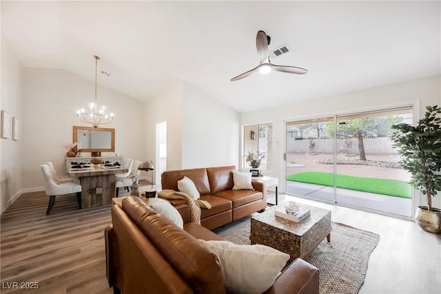 living room with lofted ceiling, wood-type flooring, and ceiling fan with notable chandelier