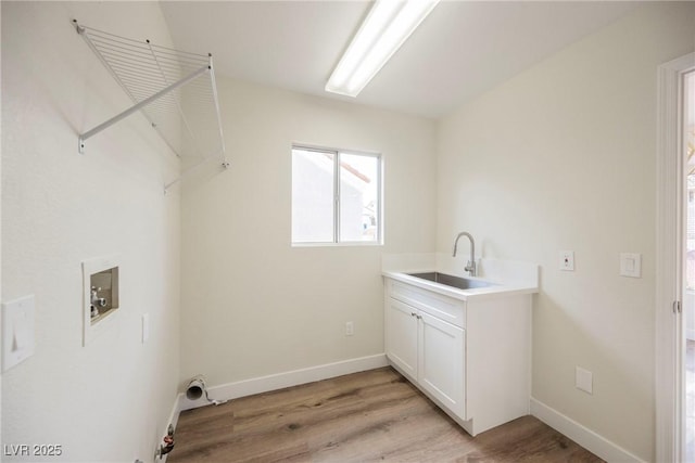 clothes washing area with sink, light hardwood / wood-style floors, hookup for a washing machine, and cabinets