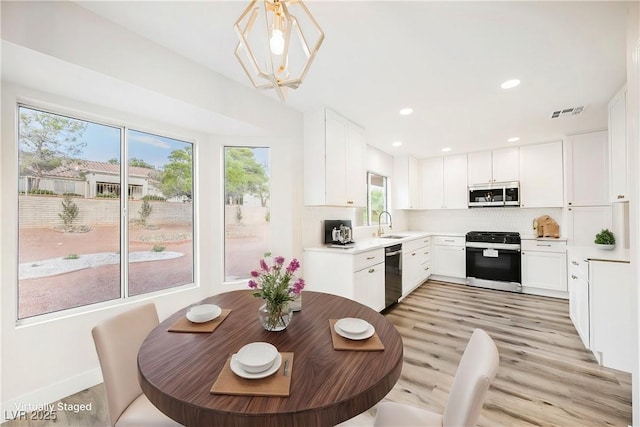 kitchen featuring white cabinets, tasteful backsplash, hanging light fixtures, and appliances with stainless steel finishes