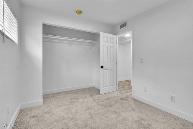 unfurnished bedroom with a closet and light carpet