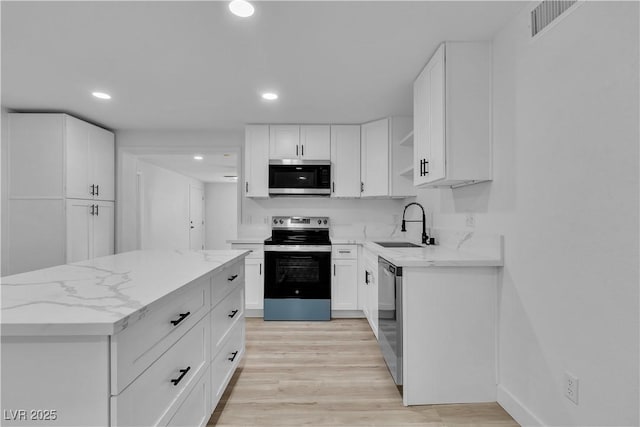 kitchen featuring white cabinetry, appliances with stainless steel finishes, light stone counters, sink, and light hardwood / wood-style flooring