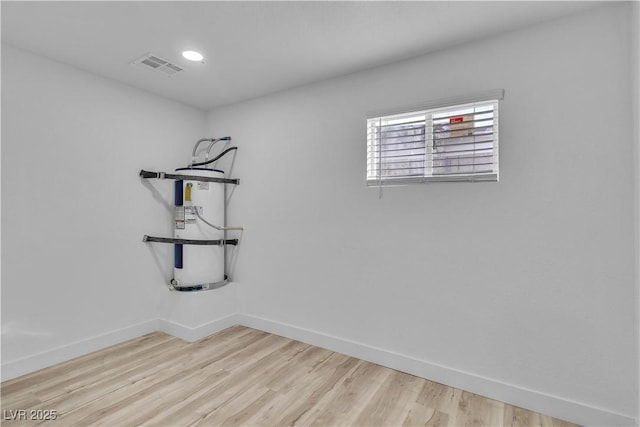 spare room featuring water heater and light hardwood / wood-style floors