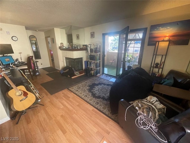 living room featuring a tiled fireplace, hardwood / wood-style floors, and a textured ceiling