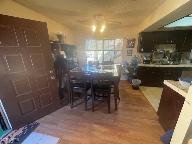 dining area with a textured ceiling, ceiling fan, light hardwood / wood-style floors, and sink