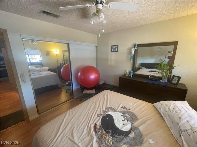 bedroom with ceiling fan, a closet, a textured ceiling, and wood-type flooring