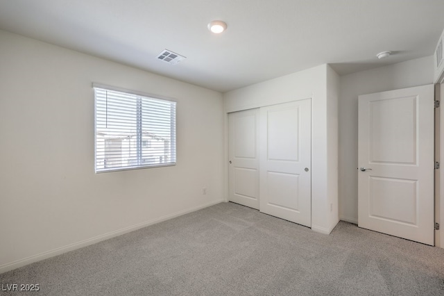 unfurnished bedroom featuring a closet and light colored carpet