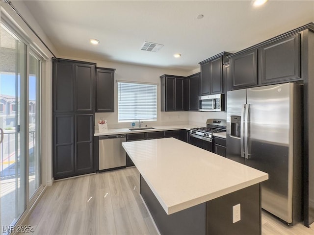 kitchen featuring stainless steel appliances, a center island, a wealth of natural light, sink, and light hardwood / wood-style flooring