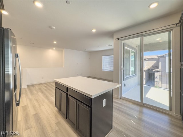 kitchen with a kitchen island, stainless steel refrigerator, and light hardwood / wood-style floors