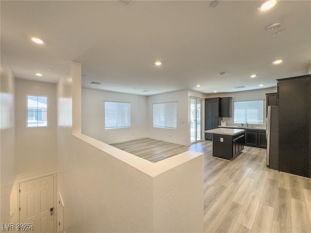 kitchen with sink, stainless steel fridge, light hardwood / wood-style floors, and a center island