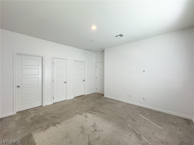 unfurnished bedroom featuring multiple closets and carpet