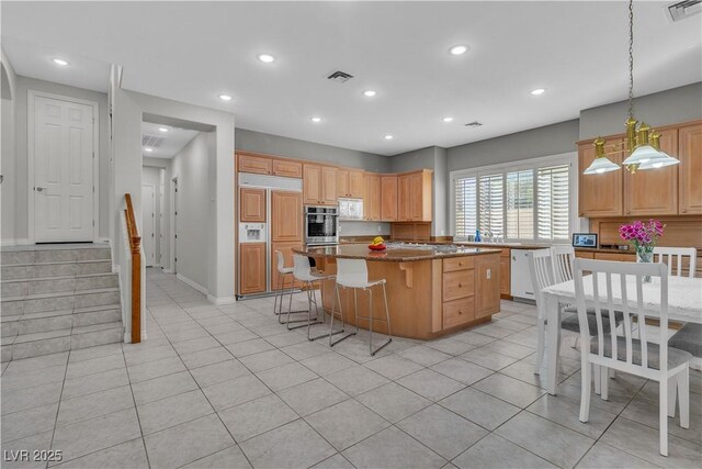 kitchen with a center island, light tile patterned flooring, white dishwasher, paneled fridge, and a breakfast bar area