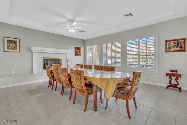 dining area featuring a tiled fireplace, ceiling fan, and light tile patterned floors