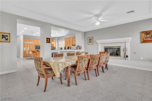 tiled dining space with a tiled fireplace and ceiling fan