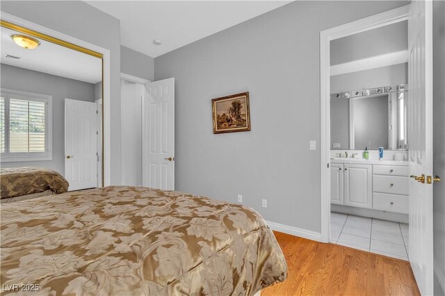 bedroom with sink, light hardwood / wood-style floors, and connected bathroom