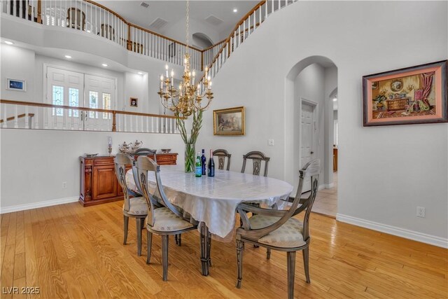 dining room featuring a high ceiling, a notable chandelier, and light hardwood / wood-style flooring