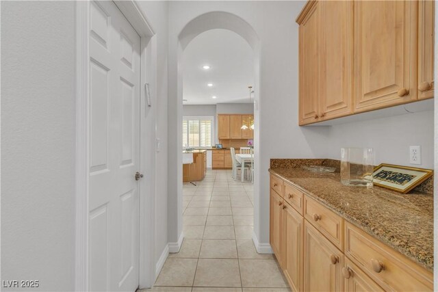 kitchen with stone counters, light tile patterned floors, and light brown cabinets