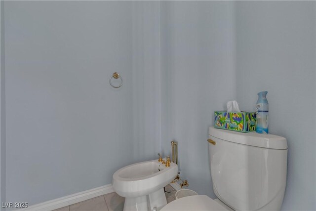 bathroom featuring toilet, tile patterned flooring, and a bidet